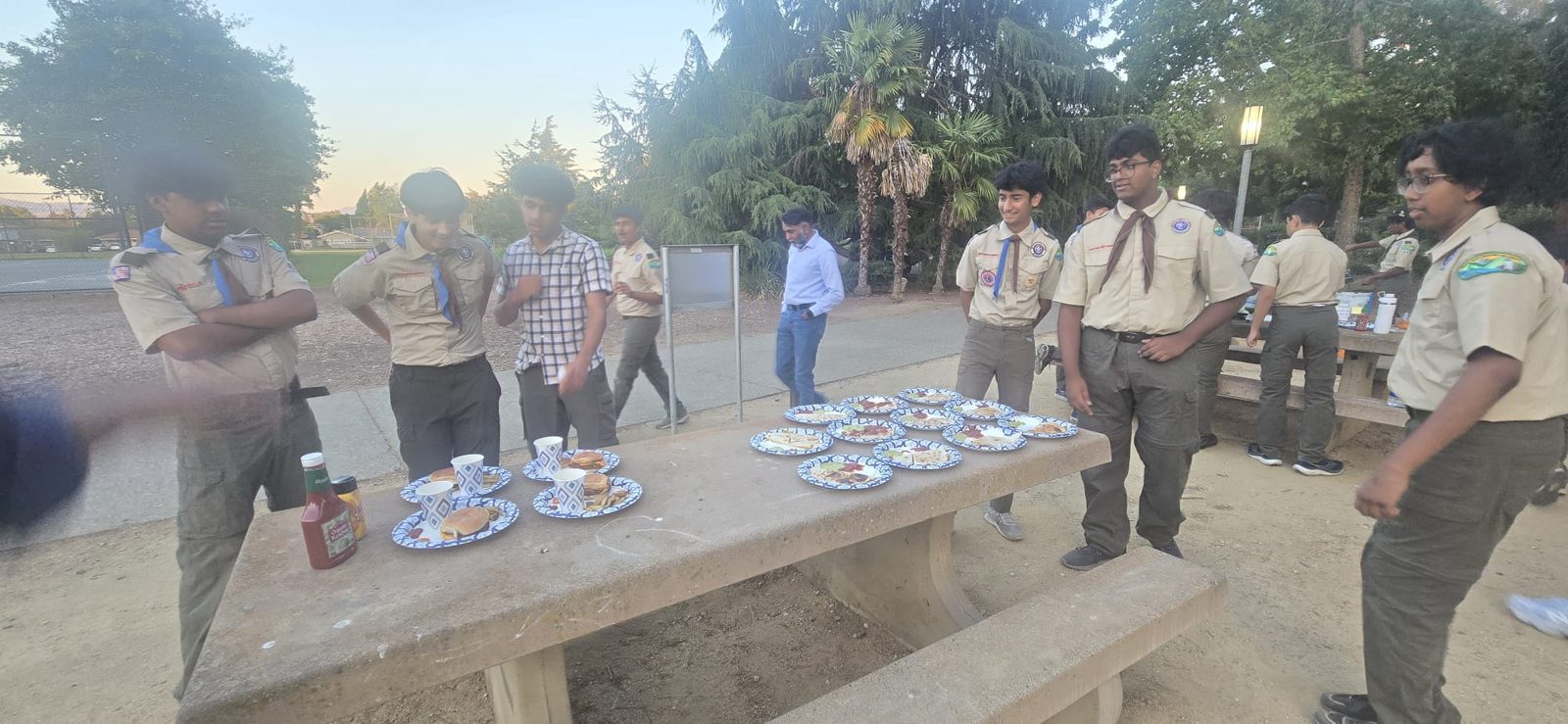 Scouts serving food at a park picnic table